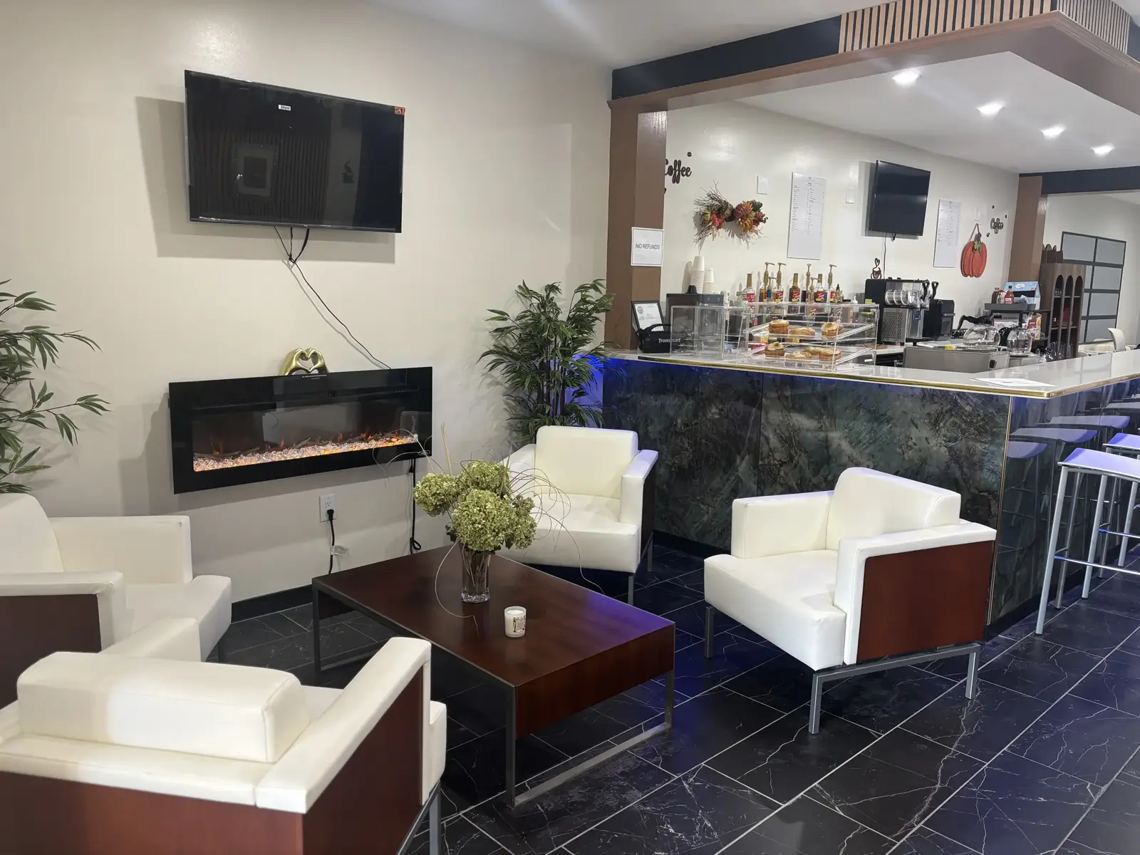 White leather lounge chairs and a fireplace facing Oak's green marble coffee bar
